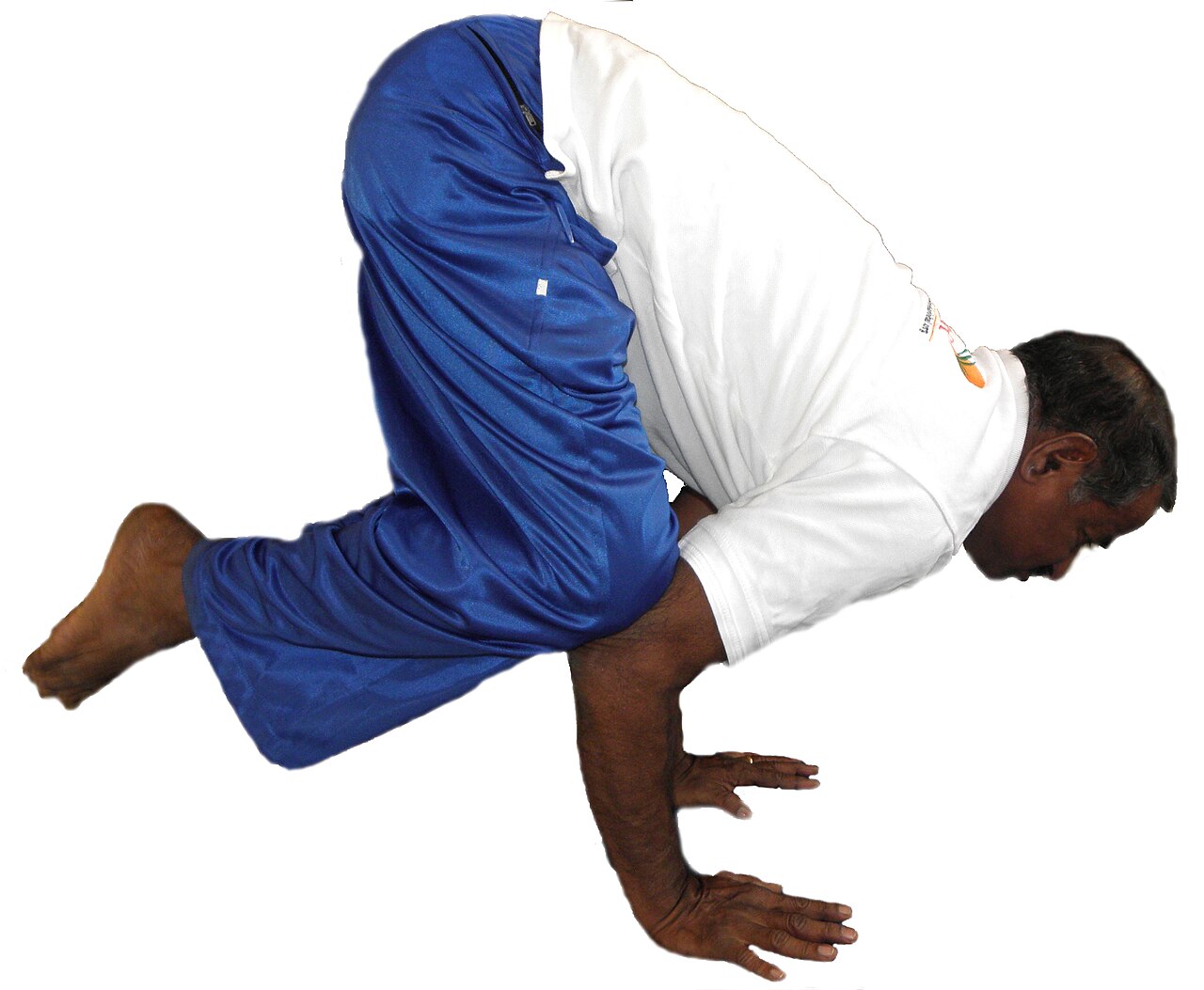 A person balancing in Crow Pose with knees on the upper arms and feet off the floor