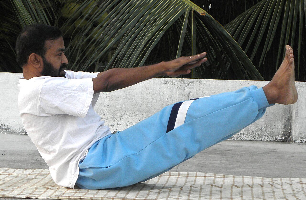 A person balancing in Boat Pose with legs lifted and arms reaching forward