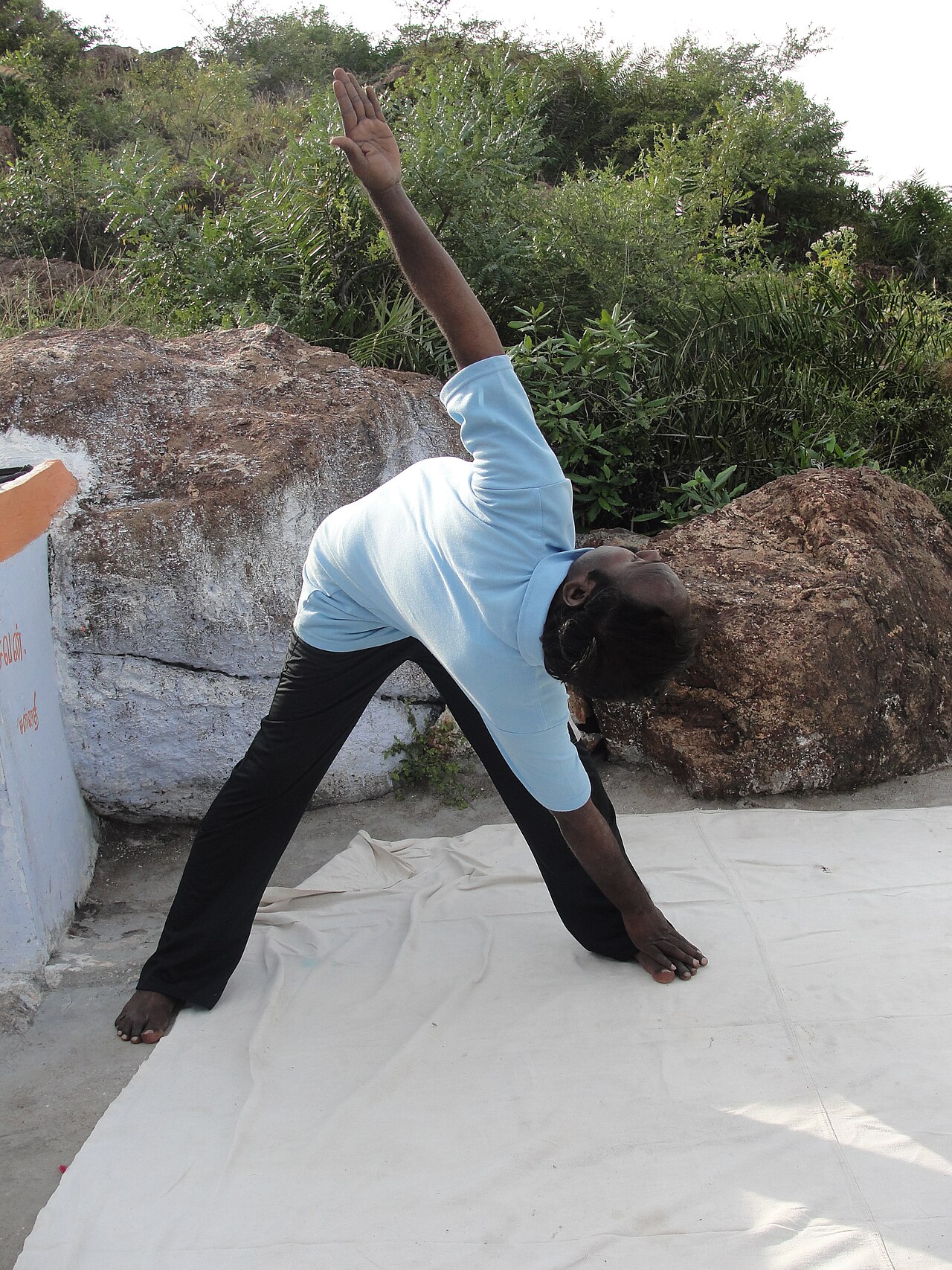 A person in Revolved Triangle Pose, twisting the torso with one hand on the floor and the other arm lifted