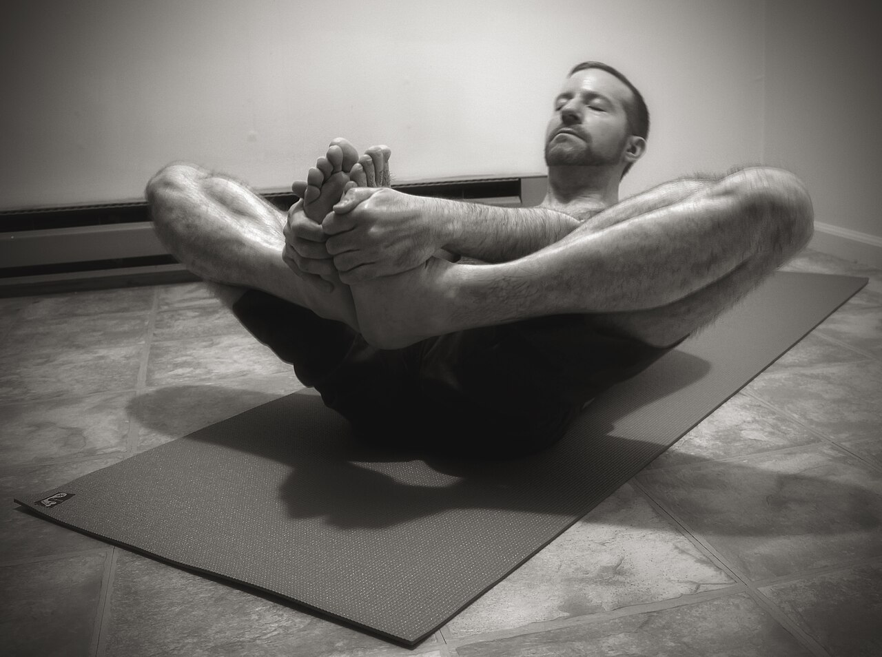 A person lying back in Reclined Bound Angle Pose with the soles of the feet together