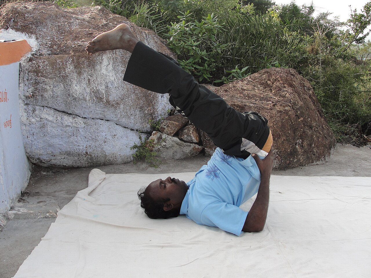 A person lying on the back with legs raised in Legs-Up-the-Wall Pose
