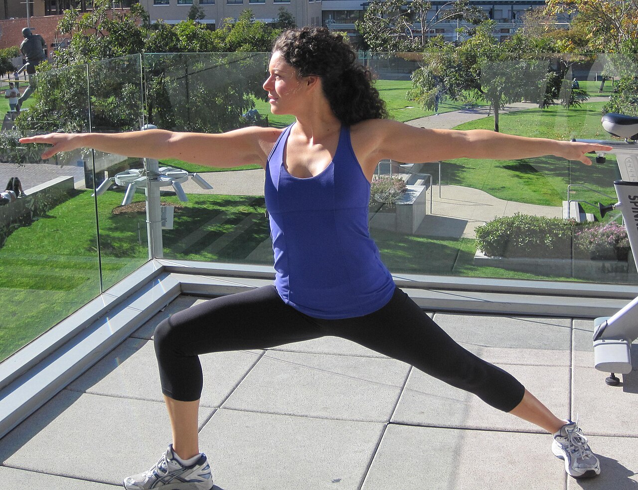 A person in Warrior II with a wide stance, front knee bent and arms extended to the sides